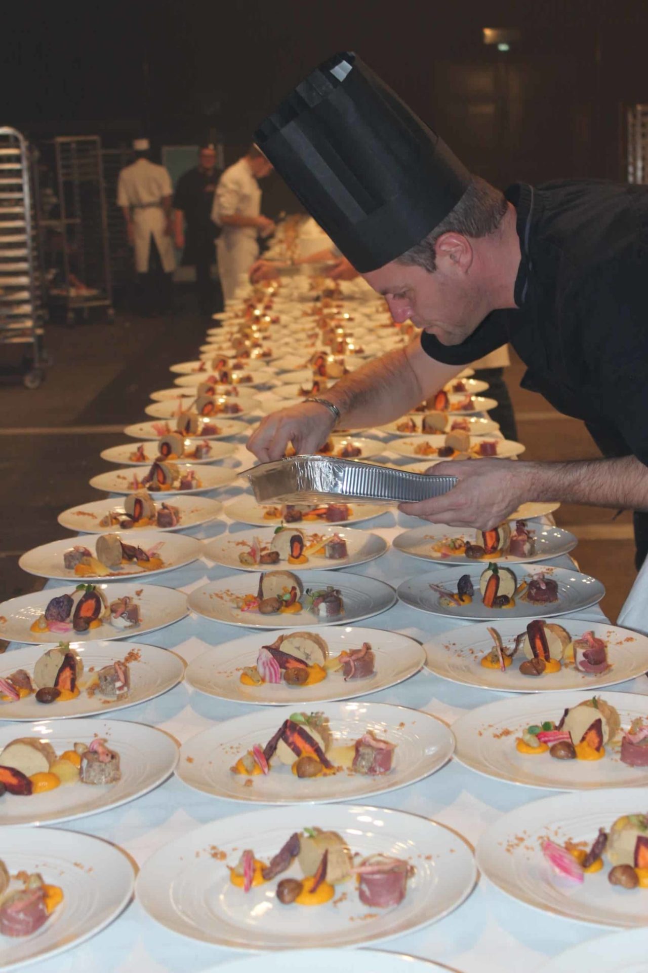 Photo du chef de cuisine entrain de dresser les assiettes d'entrées au foie gras pour 1200 personnes Montrognon Traiteur